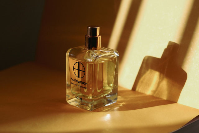 Vanilla amber perfume bottle with raw amber resin and vanilla pods on marble